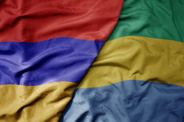 big waving national colorful flag of gabon and national flag of armenia .
