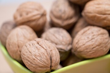 Fresh Walnuts: A Rustic Display in a Vibrant Green Bowl, Experience the rustic charm with this close-up shot of fresh, uncracked walnuts nestled in a vibrant green bowl. The detailed texture of shells
