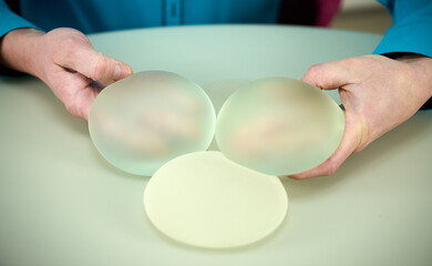 Close-up of female plastic surgeon demonstrates breast implants to a patient for her new breast....