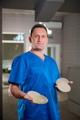 Female plastic surgeon demonstrates breast implants to a patient for her new breast. The plastic...