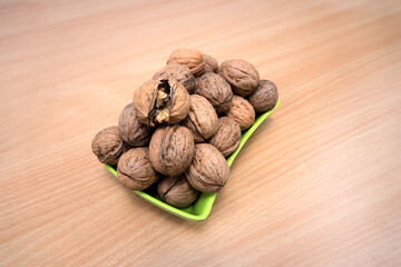 Fresh Walnuts on a Green Tray: A Feast for the Eyes and the Palate, Experience the raw beauty of nature with this vibrant image of fresh, whole walnuts. One of them is cracked open to reveal