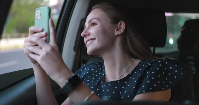 Young happy smiling woman tourist making picture or video for memorize the moment with smartphone while traveling and seeing new places during her holiday vacation trip by car with parents or friends.