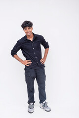 Naklejka premium Full-length portrait of a confident young Indian man with a cheerful expression, wearing casual black attire.