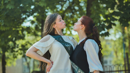 Two high school senior girls playfully sort of kissing.