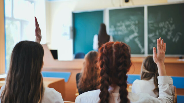 Girl students raise their hands in math class. - Powered by Adobe