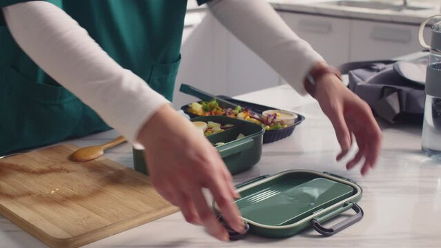 Close up of hands of unrecognizable female nurse in uniform packing container with lunch for work