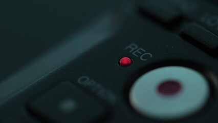 Red recording light glows after Finger Pressing the Record Button on Audio Device. Close-up, shallow dof.