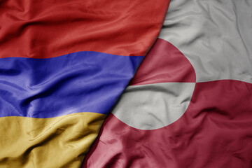 big waving national colorful flag of greenland and national flag of armenia .