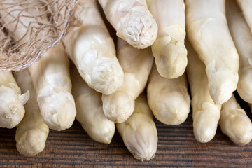 Close-up of the heads of a bunch of white asparagus spears on a rustic board