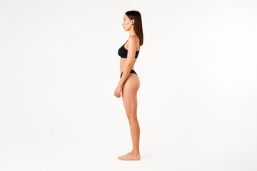 Profile view of full length portrait of beautiful sensual slim woman in black underwear