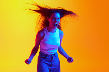 Negative emotions. Portrait of young woman aggressively shouting clenched fists against gradient studio background in neon light. Concept of human emotions, facial expression, beauty, youth. Ad