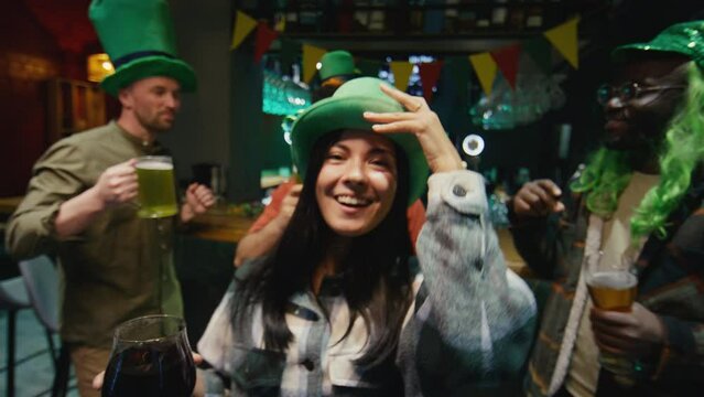 POV footage of attractive Biracial woman in green hat partying with friends in club with alcohol celebrating Saint Patricks Day