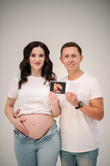 Pregnant couple holding in hands an ultrasound scan of their baby. Happy family pregnancy,...