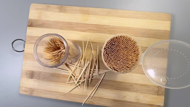 Wood toothpicks in plastic containers on cutting board, top view