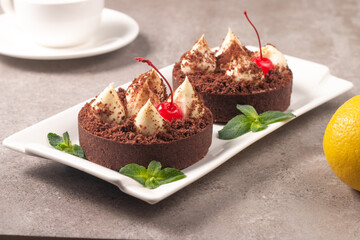 Delicious chocolate tart garnish with cherry and mint. Classic dessert. - 745728427