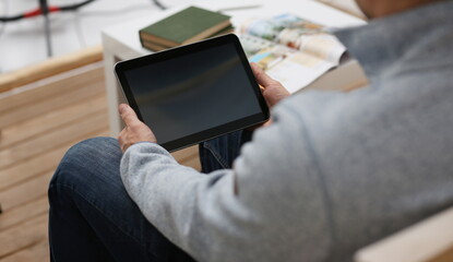 Male hand holds tablet in home setting while
