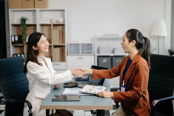 Businesswomen work and discuss their business plans. A Human employee explains and shows her colleague the results paper