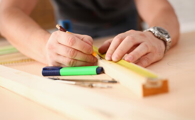 Arms of worker measuring wooden bar