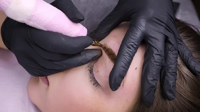 Permanent eyebrow makeup procedure, the introduction of pigments into the skin of the eyebrows. Permanent makeup procedure, performing PMU of eyebrows