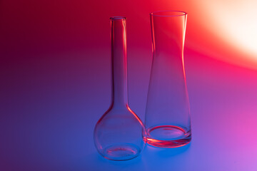 Close-up of two decorative glass vases on a red, blue and violet colored background