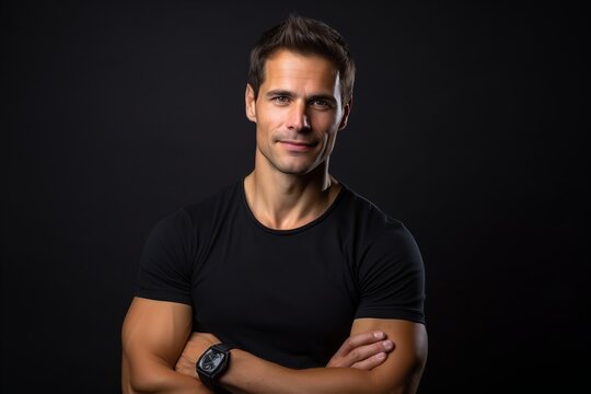 Portrait of a handsome man with arms crossed on black background.
