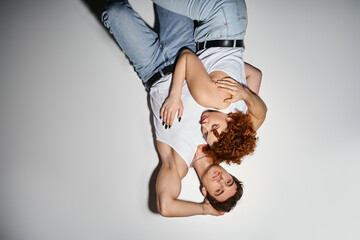 handsome man in jeans lying on floor next to his young girlfriend and looking at camera, sexy couple