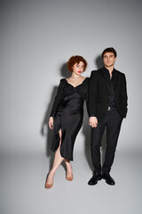 attractive man in black suit looking at camera next to his appealing girlfriend, sexy couple