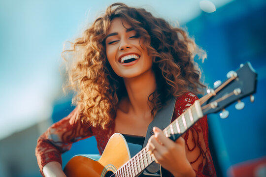 Young happy woman plays guitar and sings