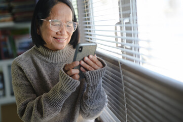 closeup and senior hands with a smartphone,using applications on smartphone. woman chatting in messenger or social network with friends or children, shopping in internet store. having fun at home