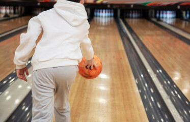 Rear view of boy holding bowling ball while standing in bowling alley in shooting position
