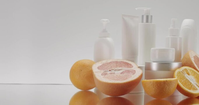 Set of professional cosmetic for skincare and bodycare in white empty packaging near oranges. Advertising concept of beauty products. Body lotion tube, face cream in jar and cleansing gel in bottle 