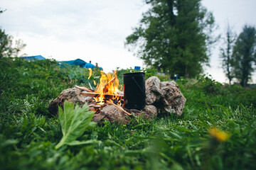 A campfire glowing in the grass near a water bottle under the night sky