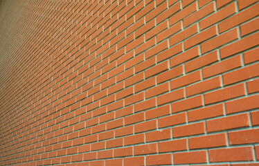 The texture of a high brick wall from a many rows of red bricks stretching into perspective