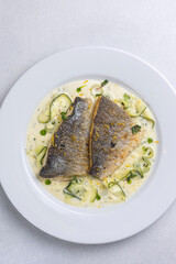 Baked fish with zucchini and dill on a white plate
