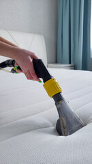 A woman's hand cleans a modern white mattress with a professional cleaning agent