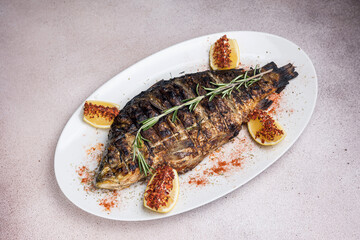 Delicious grilled fish with lemon and rosemary on a white plate
