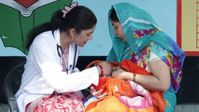 Indian pediatrician doctor examine newborn baby during a rural healthcare camp along with mother, infant care,  medical outreach in village of India