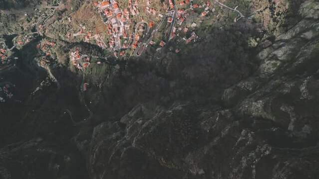 Drone flight over a cliff with camera downwards and panning up to reveal the town of Curral das Freiras, Madeira 03