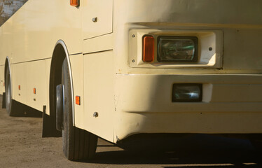 Photo of the hull of a large and long yellow bus. Close-up front view of a passenger vehicle for transportation and tourism