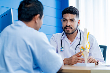 Asian male orthopedics professional doctor consulting explaining knee bone model to male patient,...