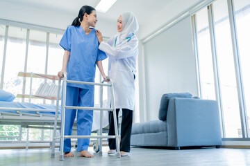 Healthcare, A Muslim Female doctor help a patient who is doing physical therapy and is practicing walking with a walking stick in the hospital. - obrazy, fototapety, plakaty