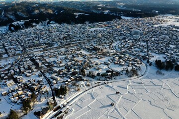 ドローン撮影：真っ白な雪に覆われた田舎町の住宅街