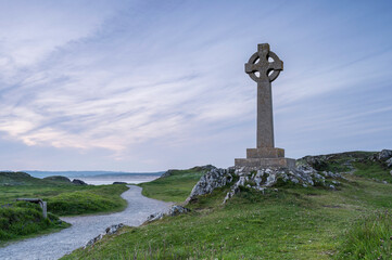 A Celtic cross on Llanddwyn, along the coast of Anglesey, Wales, near Newborough Beach. It is sunset