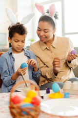 Portrait smiling African American mother and son  decoration and painting easter eggs at home....