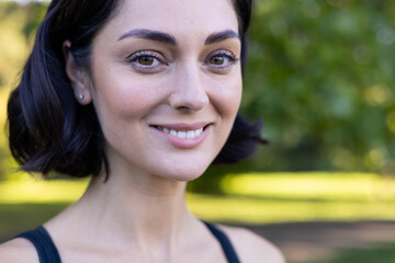 Confident young woman smiling outdoors with natural background