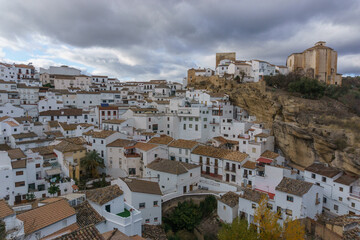 Fototapeta na wymiar View over typical andalusian village with white houses and street with dwellings built into rock overhangs, Setenil de las Bodegas, Andalusia, Spain