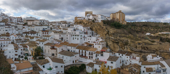 Fototapeta na wymiar View over typical andalusian village with white houses and street with dwellings built into rock overhangs, Setenil de las Bodegas, Andalusia, Spain
