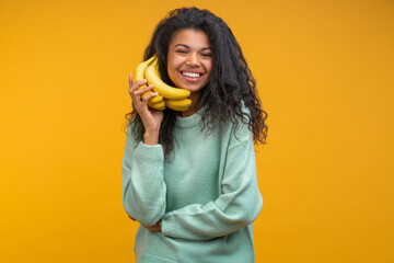 Studio portrait of funny positive casually dressed girl pretending to make a call via banana phone isolated over bright colored orange yellow background - 745786639