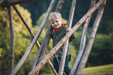 Adorable Cute Blond Boy in Nature between Wooden Logs - 745787076
