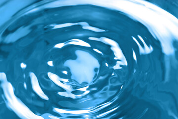 Splash of clear water on blue background, closeup
